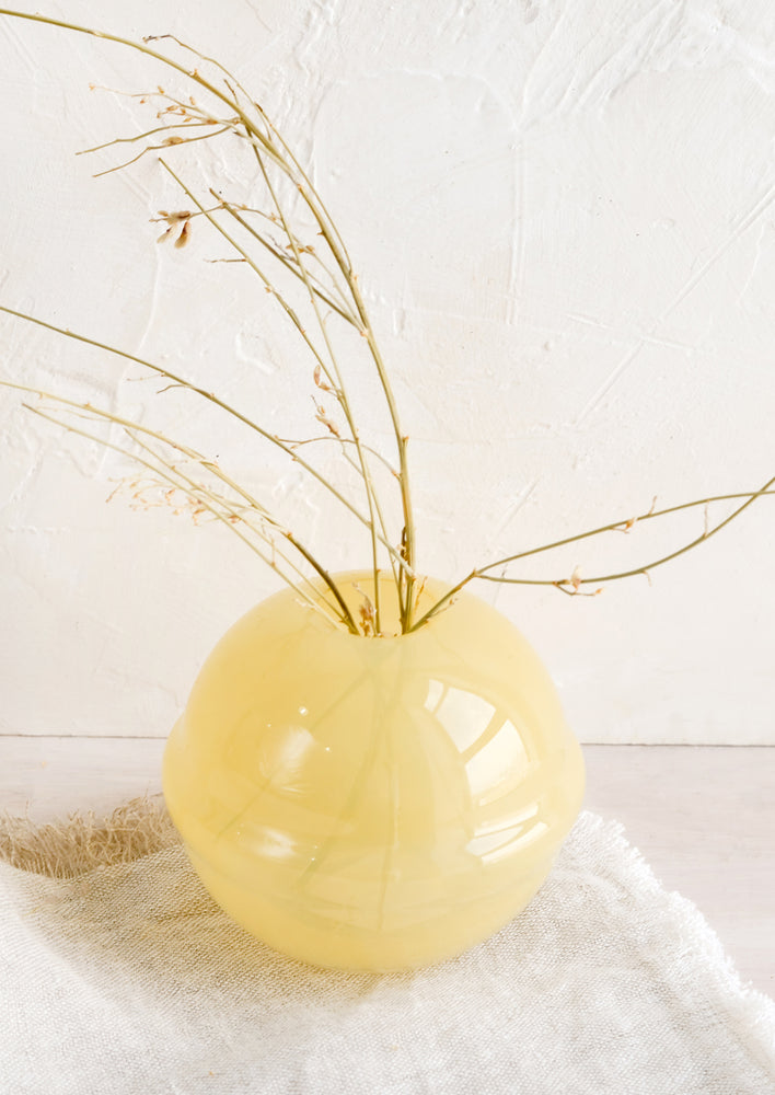 A spherical glass vase in translucent yellow.