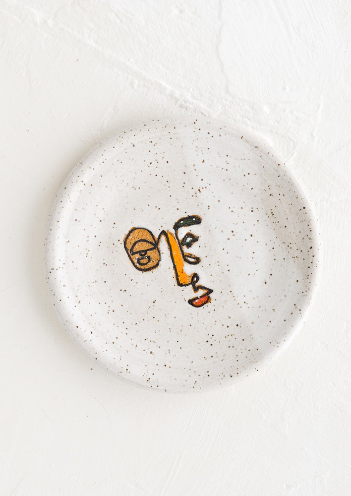 A small speckled ceramic trinket dish with and painted expressionist faces.