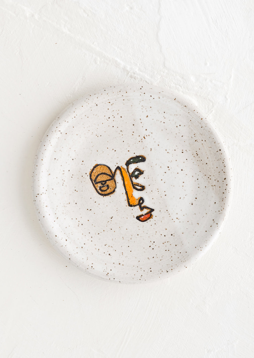Multicolor: A small speckled ceramic trinket dish with and painted expressionist faces.