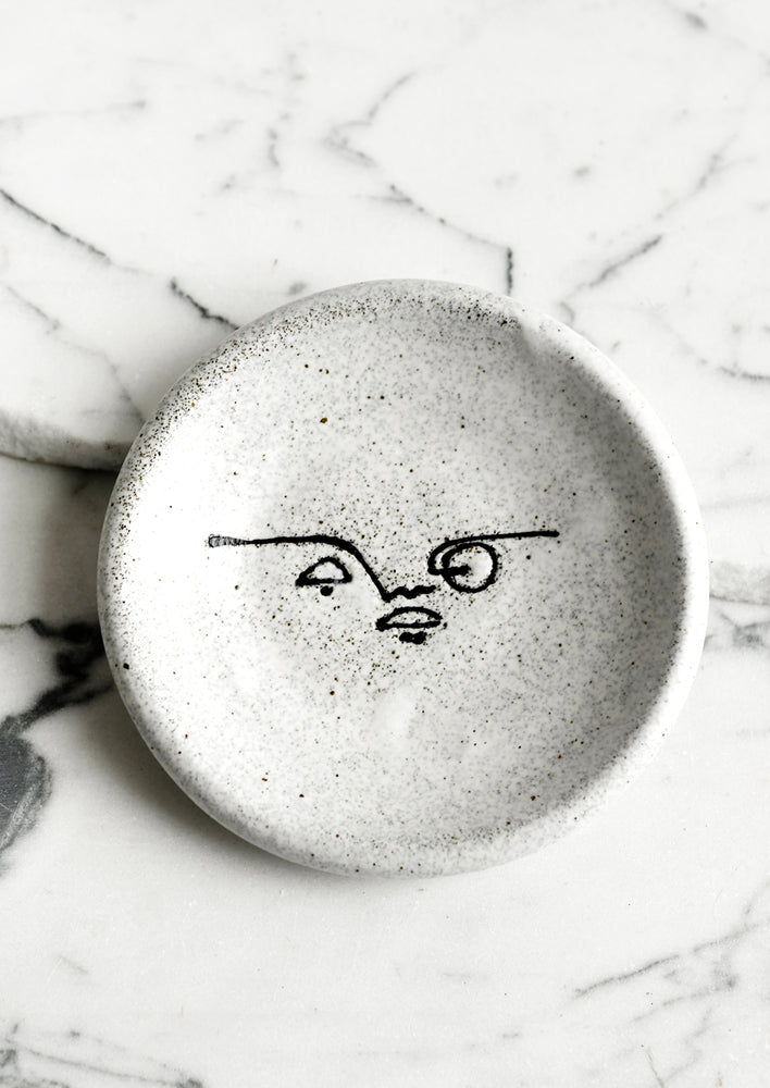 A small speckled ceramic trinket dish with and painted expressionist faces.