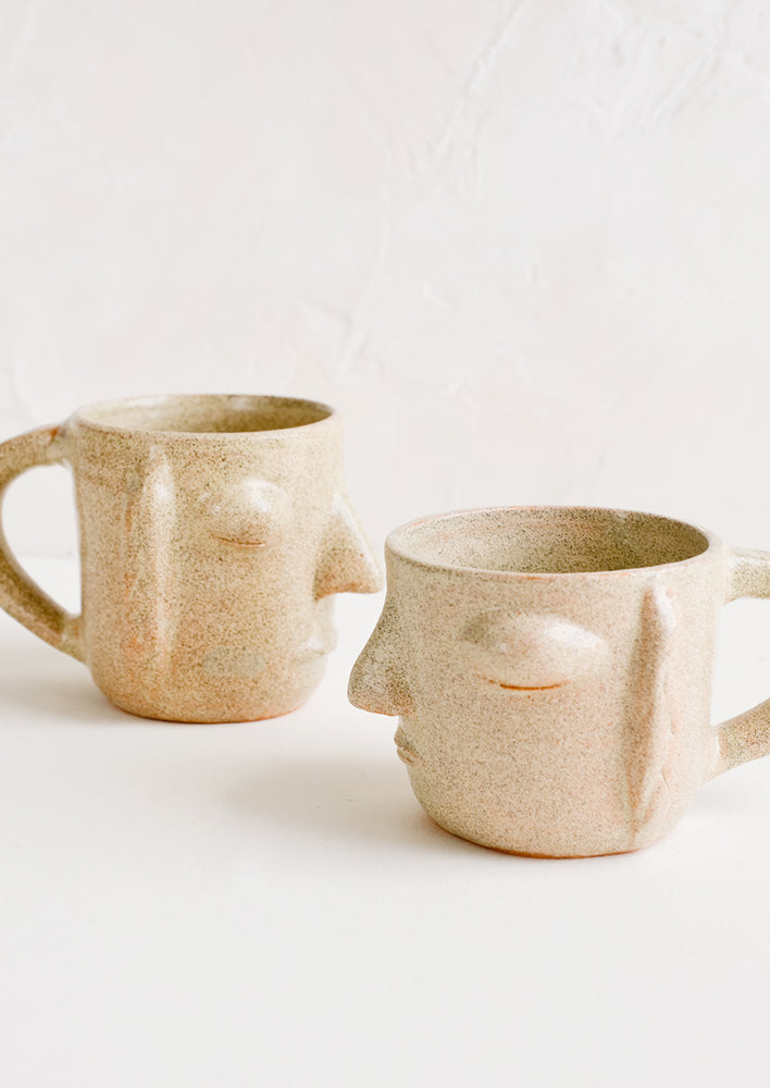3: Two face shaped mugs in speckled sandy clay.