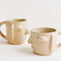3: Two face shaped mugs in speckled sandy clay.