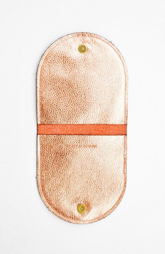 3: A metallic copper half-oval wallet opened to expose the interior pockets, snaps, and brand logo.