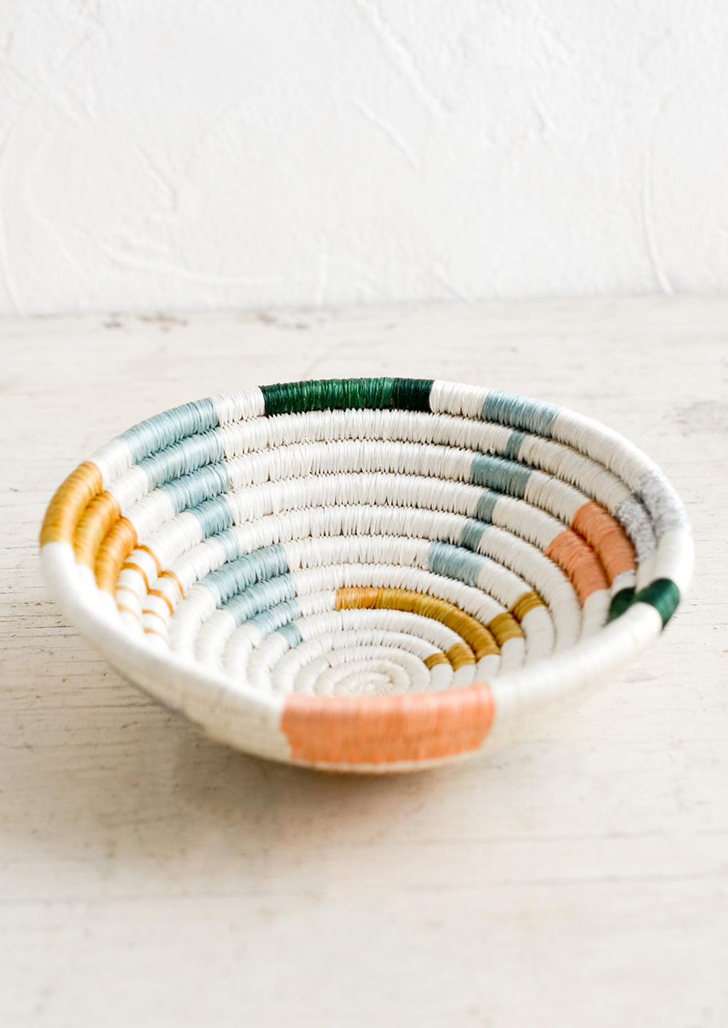 2: A small catchall bowl made from sweetgrass in pastel colored geometric pattern.