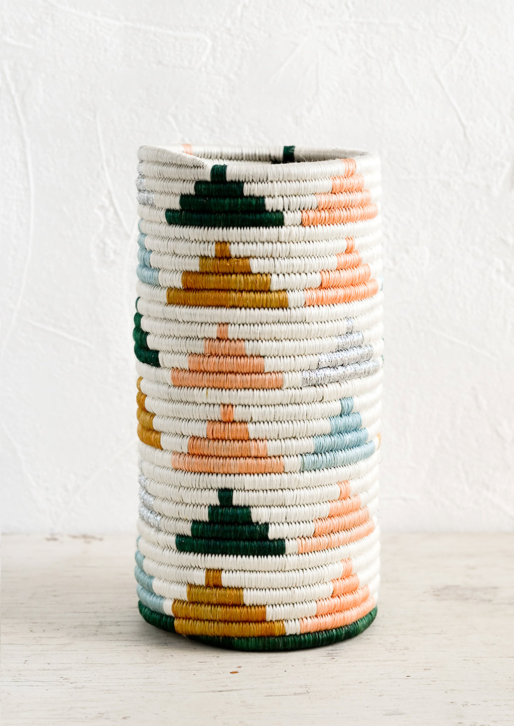 1: A woven sweetgrass vase in white with colored triangle pattern.