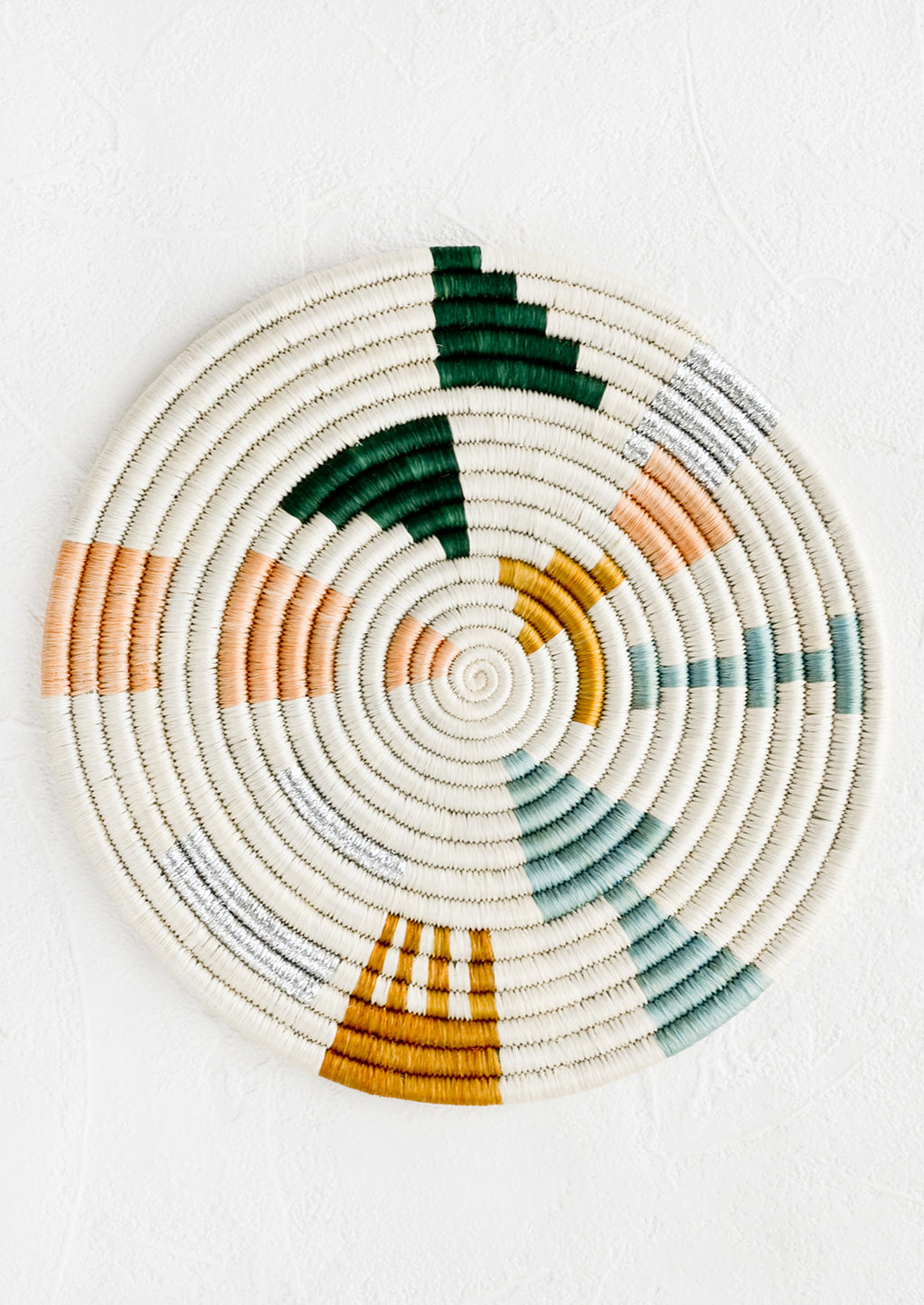 1: A round trivet in white with metallic and pastel design.