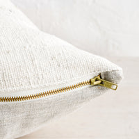 4: An exposed brass zipper on the bottom of a throw pillow.