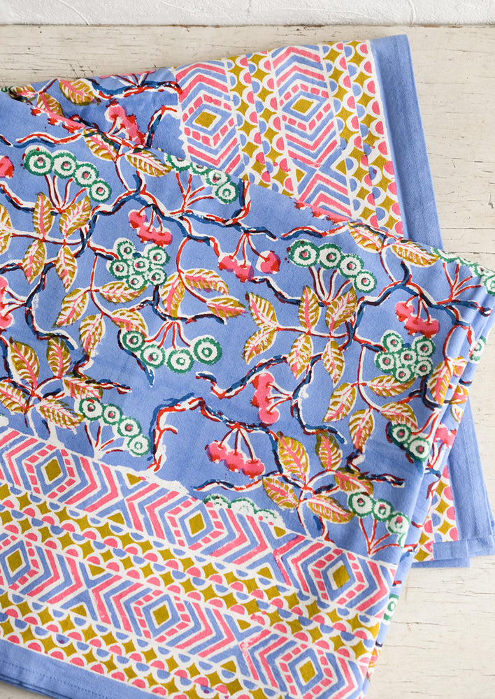 1: A block printed table cloth in yellow, blue and pink floral print with geometric border.