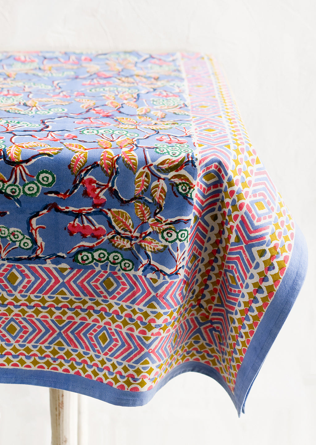 2: A block printed table cloth in yellow, blue and pink floral print with geometric border.