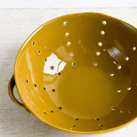 1: A large ceramic colander with side handles.