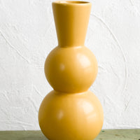 1: A yellow ceramic vase with curvy, tall silhouette.