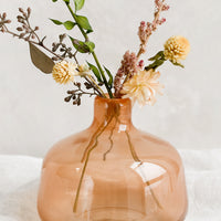 1: A peach glass bud vase with dried flowers.