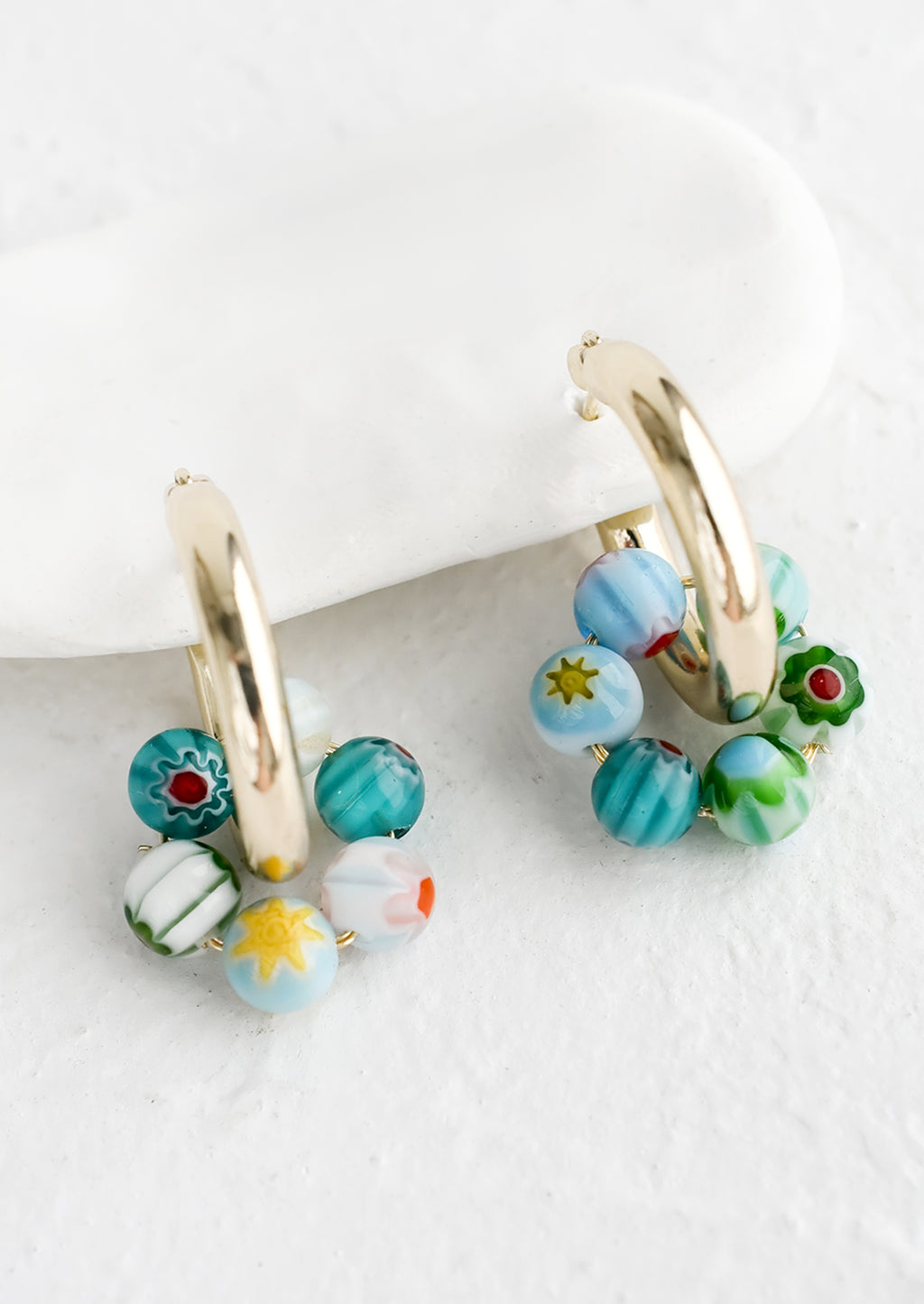 Turquoise Multi: A pair of gold hoop earrings with turquoise millefiore glass beads.