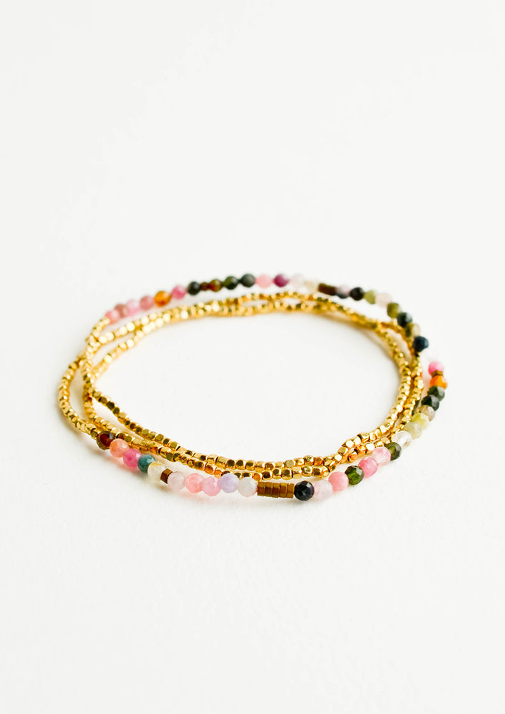 A single strand bracelet of gold and multi-colored beads wrapped upon itself in three layers. 