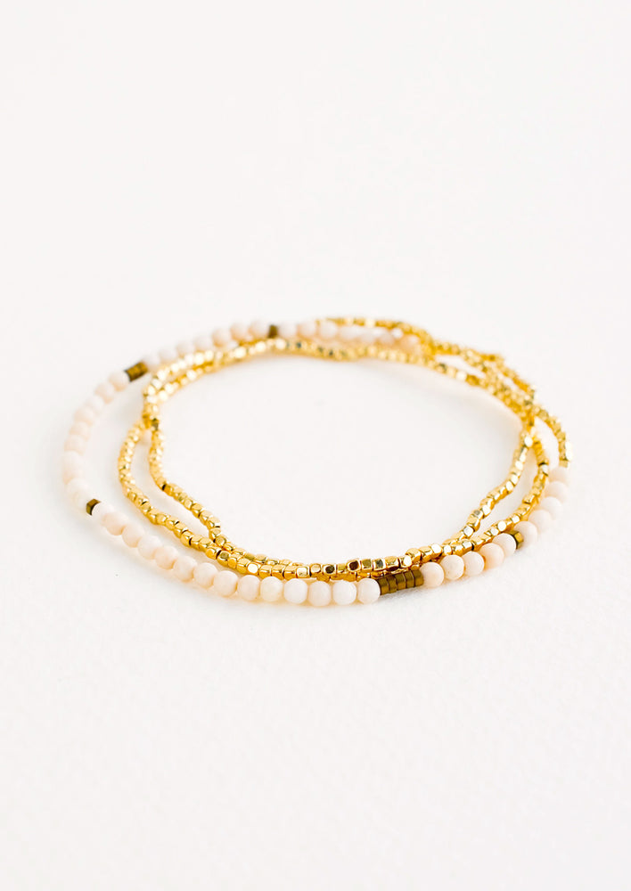 A single strand bracelet of gold and ivory beads wrapped upon itself in three layers. 
