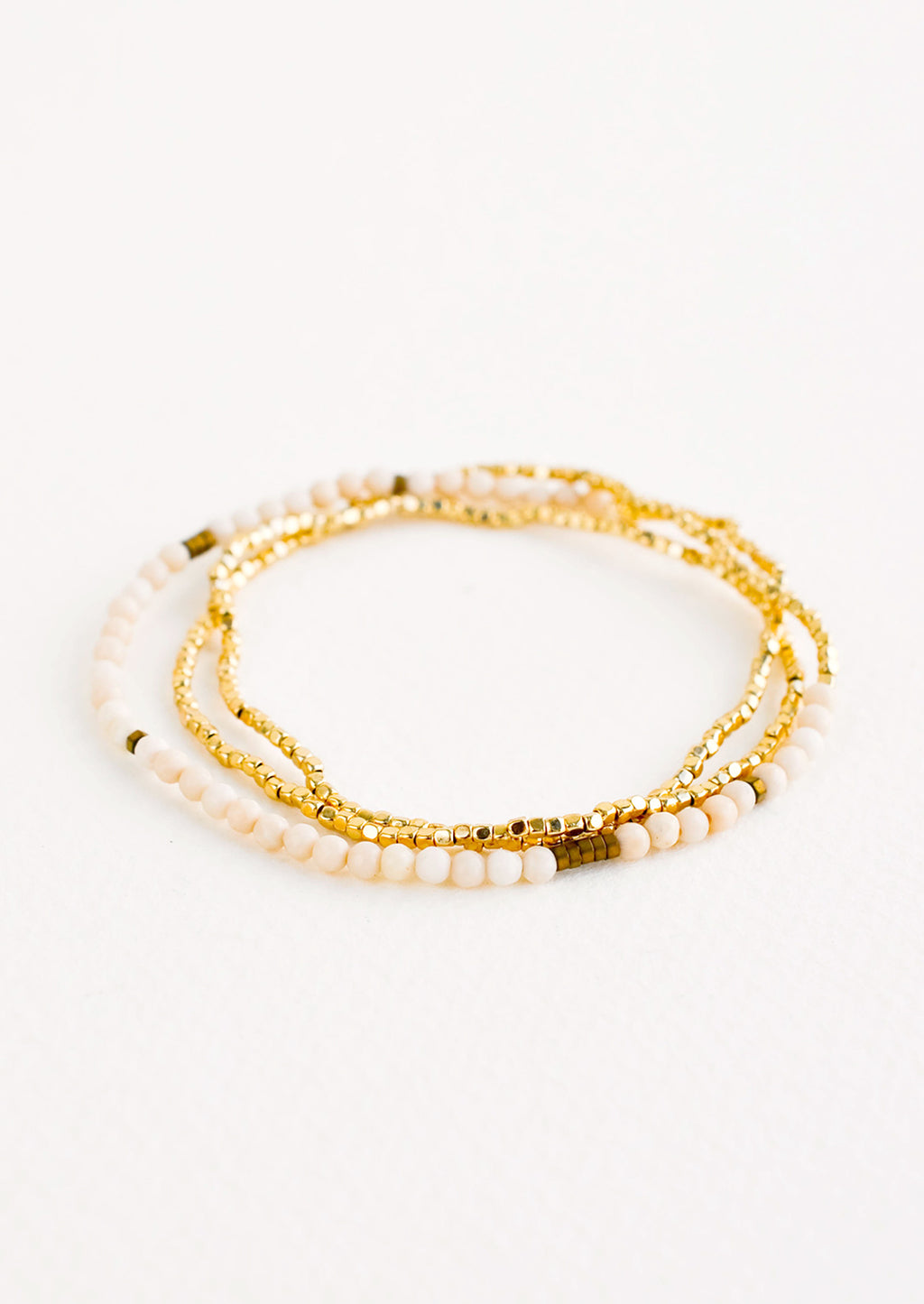 White Fossil: A single strand bracelet of gold and ivory beads wrapped upon itself in three layers. 