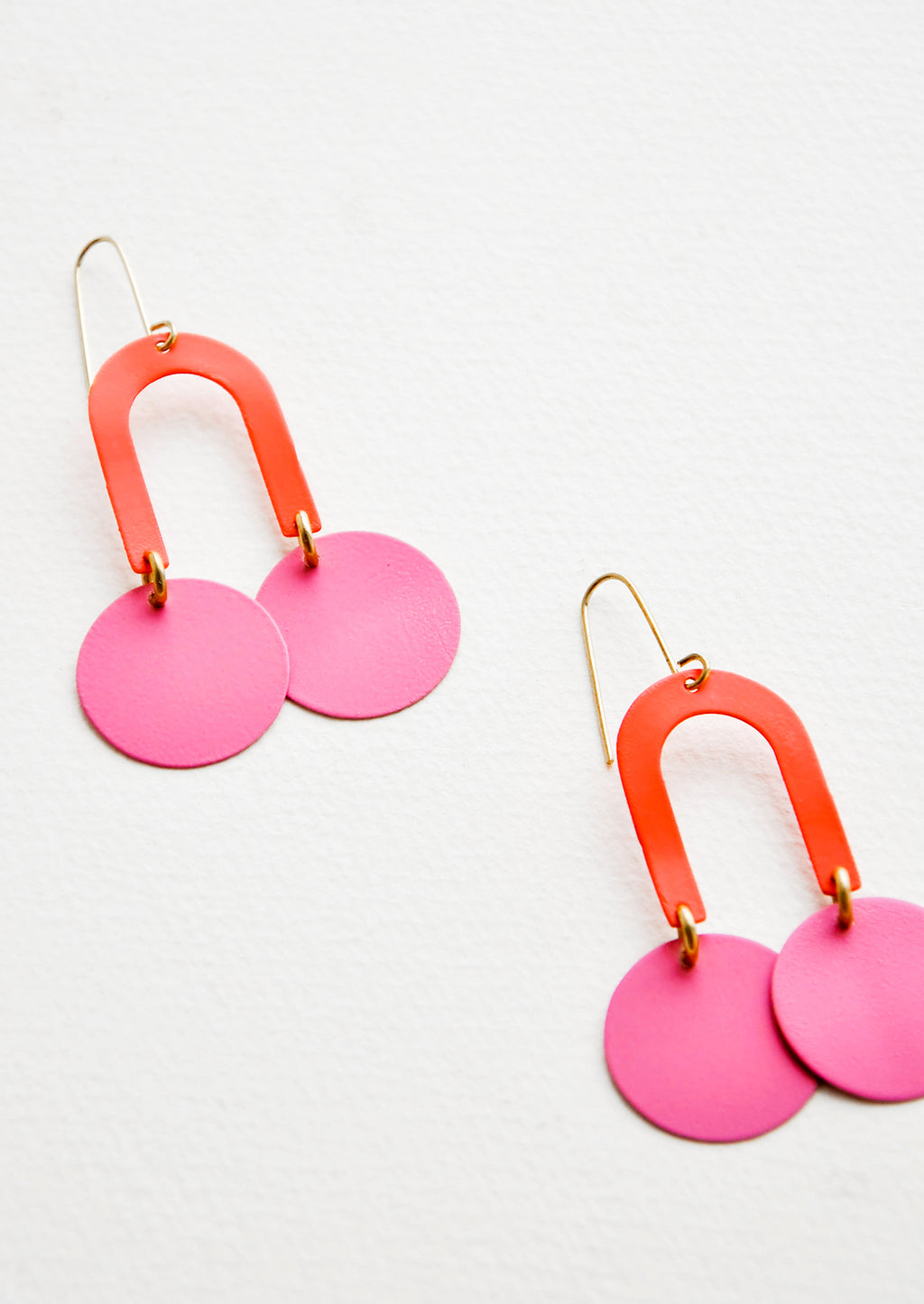 Coral / Pink: Two-toned pink earrings form a curved arc with two discs at each end.