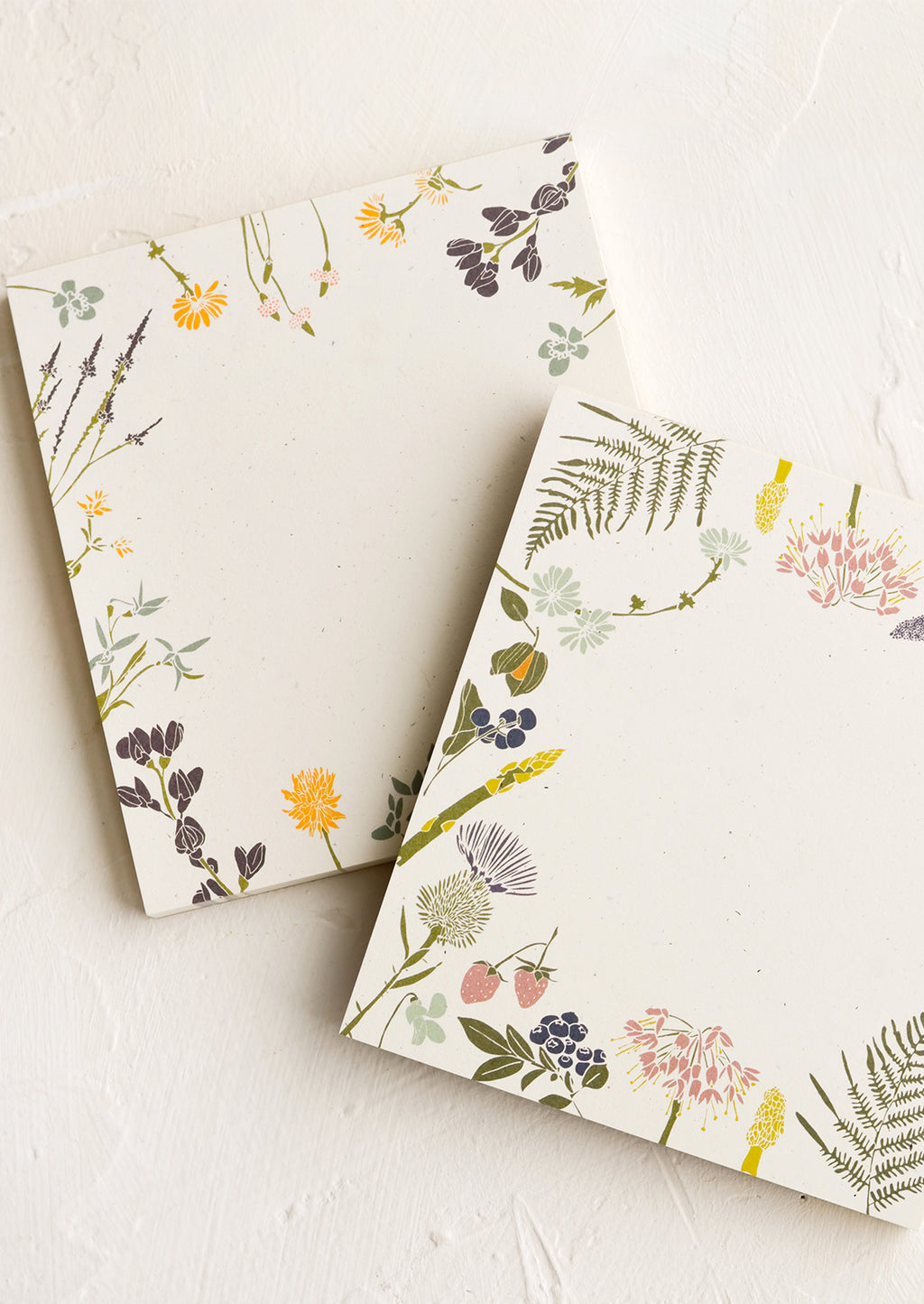 1: Two square notepads with botanical borders in different designs.