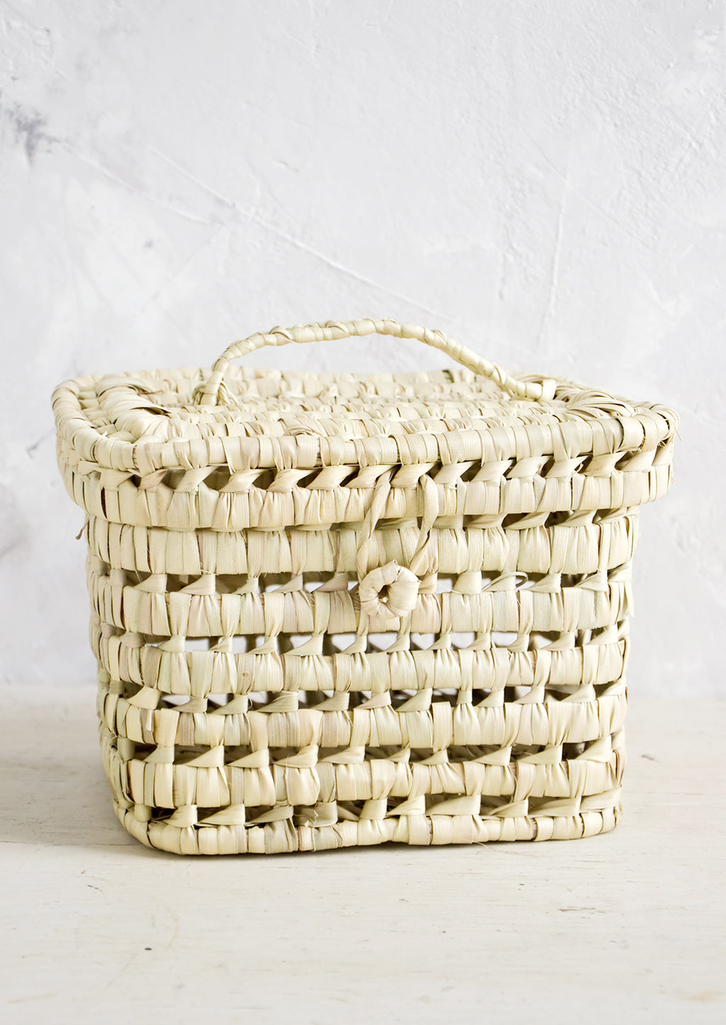 3: A square-shaped, lidded basket made from woven natural palm leaf.