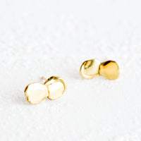 Brass: A pair of brass stud earrings featuring two drippy, melty circles stacked on each other.