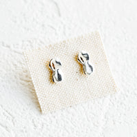 Sterling Silver: A pair of silver stud earrings on canvas card featuring a drippy, melty appearance.
