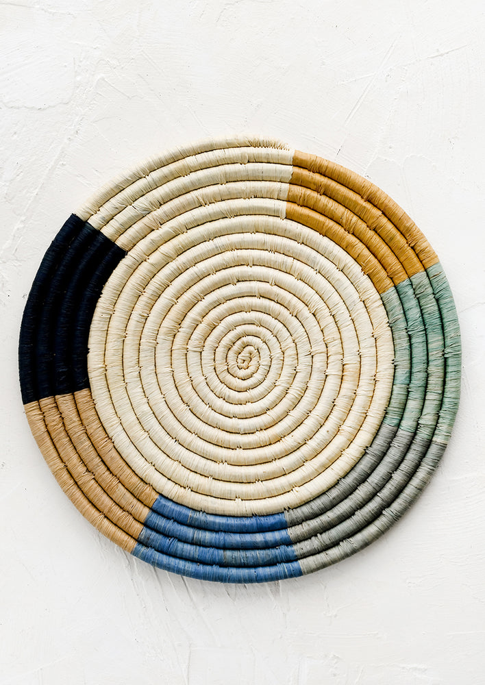 A raffia trivet with natural center and blue and tan border.