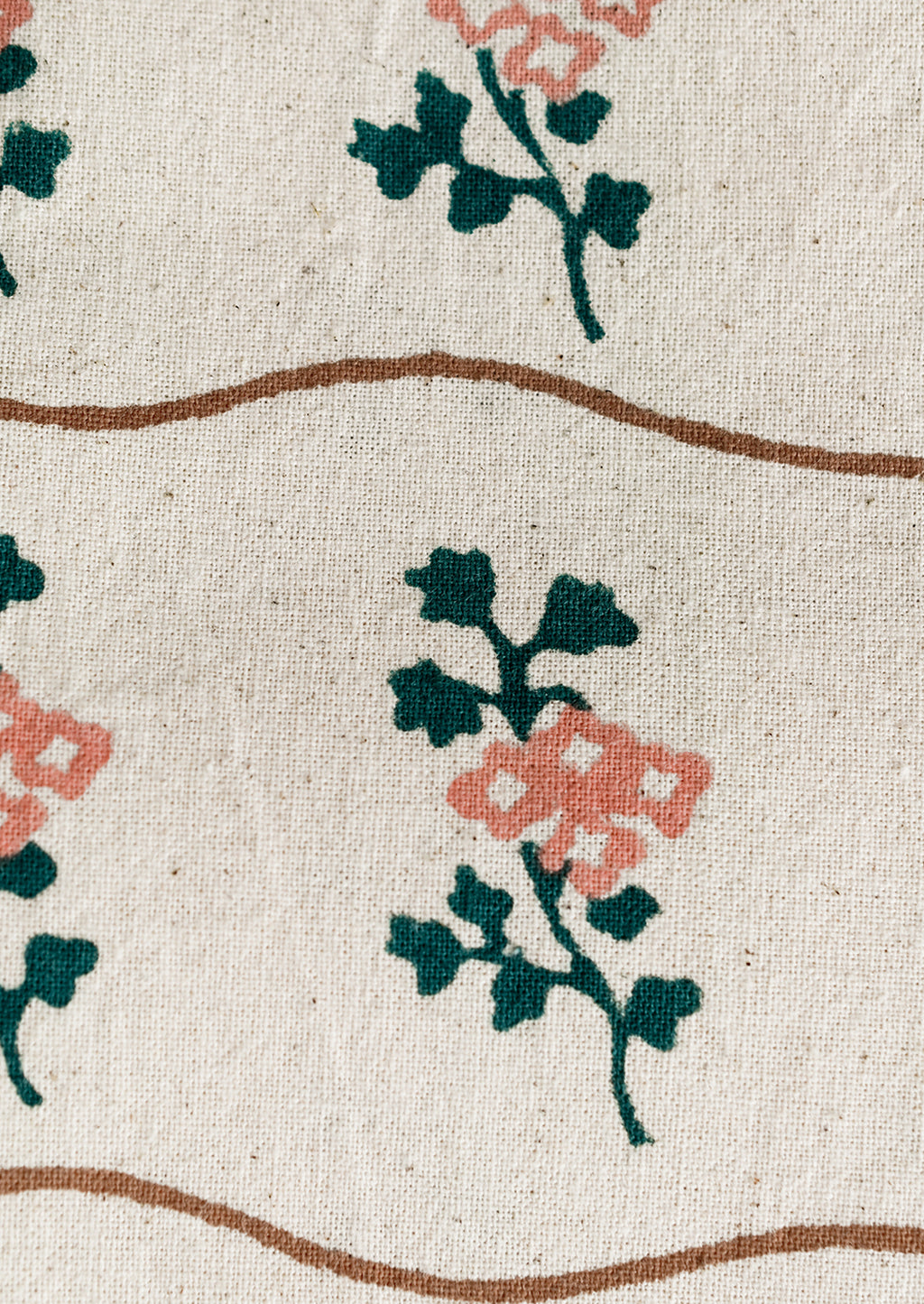4: A natural cotton napkin with wavy brown line and green/peach flower print.
