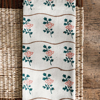 Green / Rose: A natural cotton napkin with wavy brown line and green/peach flower print.