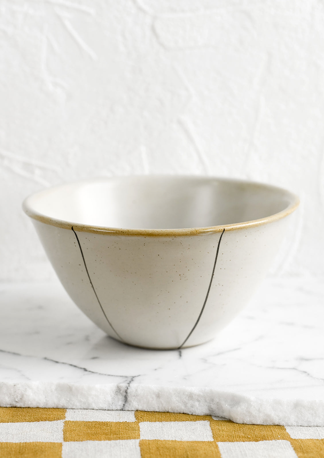 A ceramic bowl in white with thin black stripe detail.