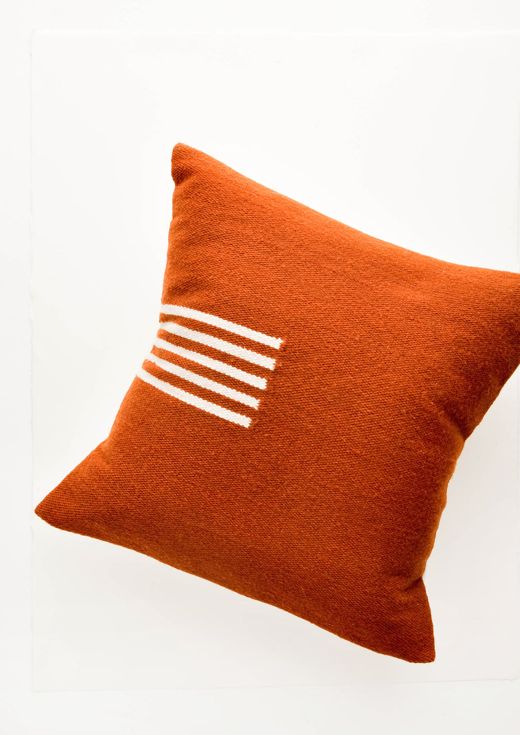 Terracotta / Natural: Terracotta colored, square wool throw pillow with contrasting small stripe detail at side.