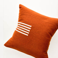 Terracotta / Natural: Terracotta colored, square wool throw pillow with contrasting small stripe detail at side.
