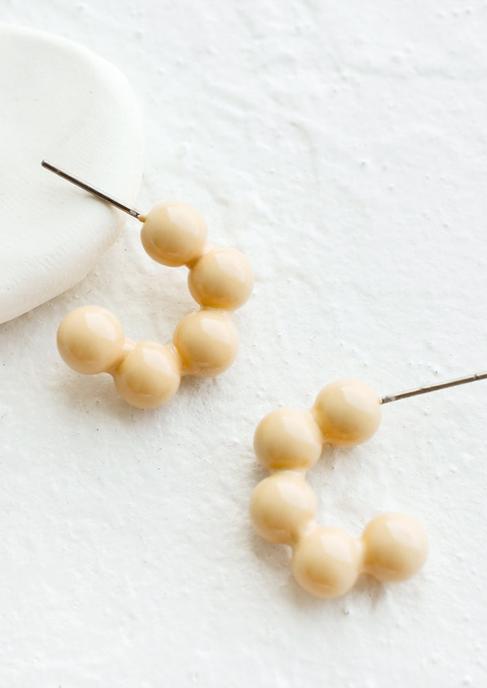Almond: Glossy ball hoop earrings in cream color.