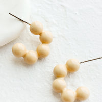 Almond: Glossy ball hoop earrings in cream color.