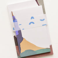 Fjord Multi: Two stacked notepads wrapped with cellophane, decorated with colorful abstract shapes.
