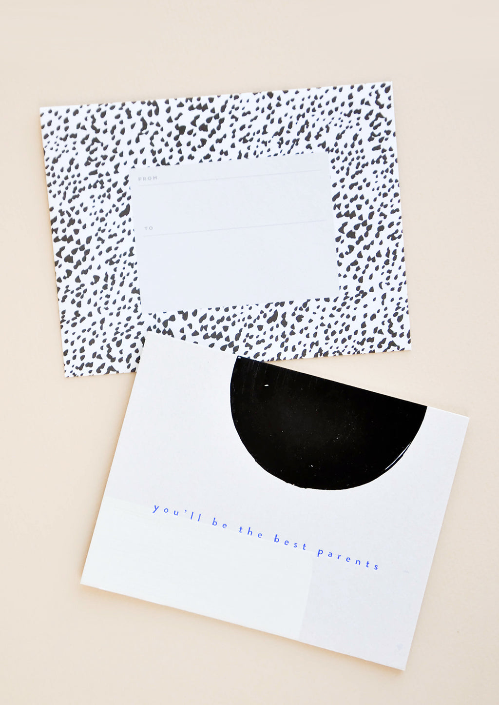 1: A black and white dotted envelope and white greeting card with a black semicircle and the text "you'll be the best parents" in blue.
