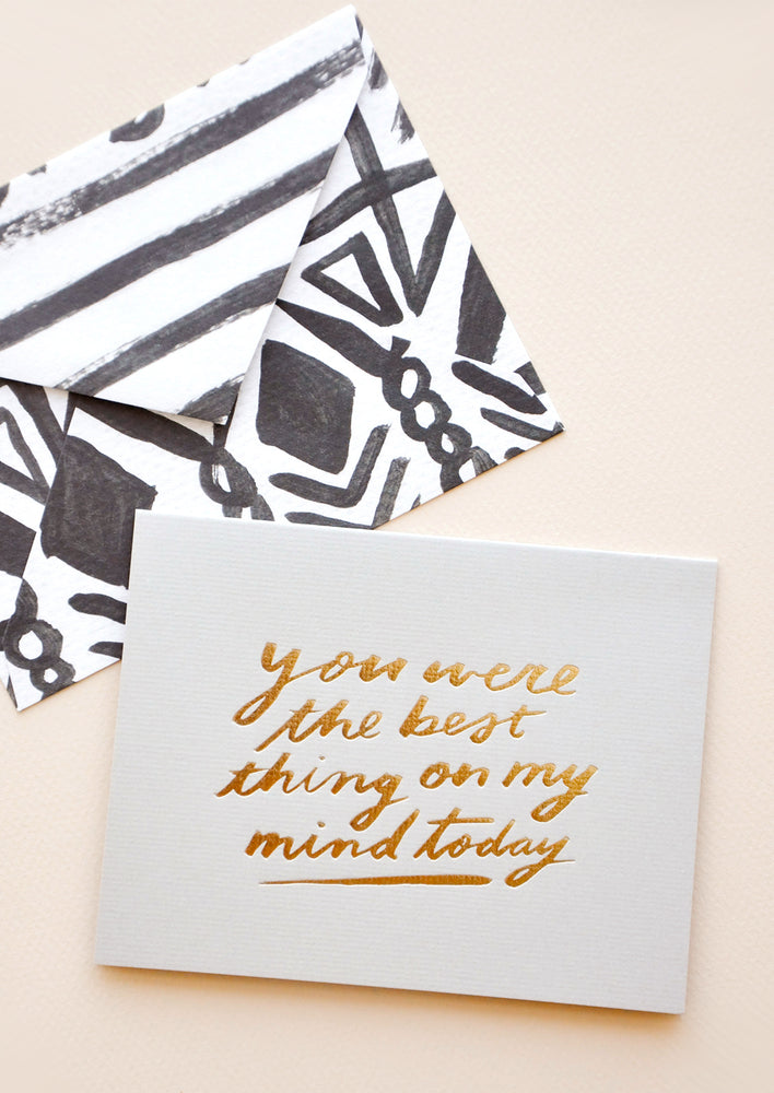 Grey greeting card with "You were the best thing on my mind today" in gold foil. Shown with black and white patterned envelope.