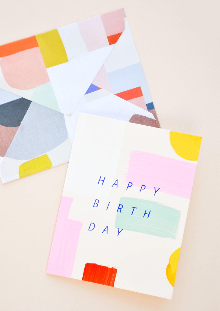 Greeting card with hand-painted colorful brushstrokes and "Happy Birthday" printed in cobalt blue