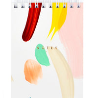 2: Small spiral bound white notepad with cover decorated in colorful, hand-painted paint strokes