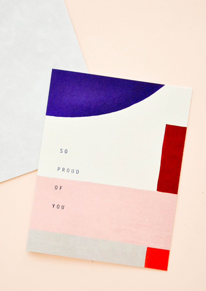 1: Notecard with cobalt blue and pink/red geometric composition, and text "So Proud Of You"