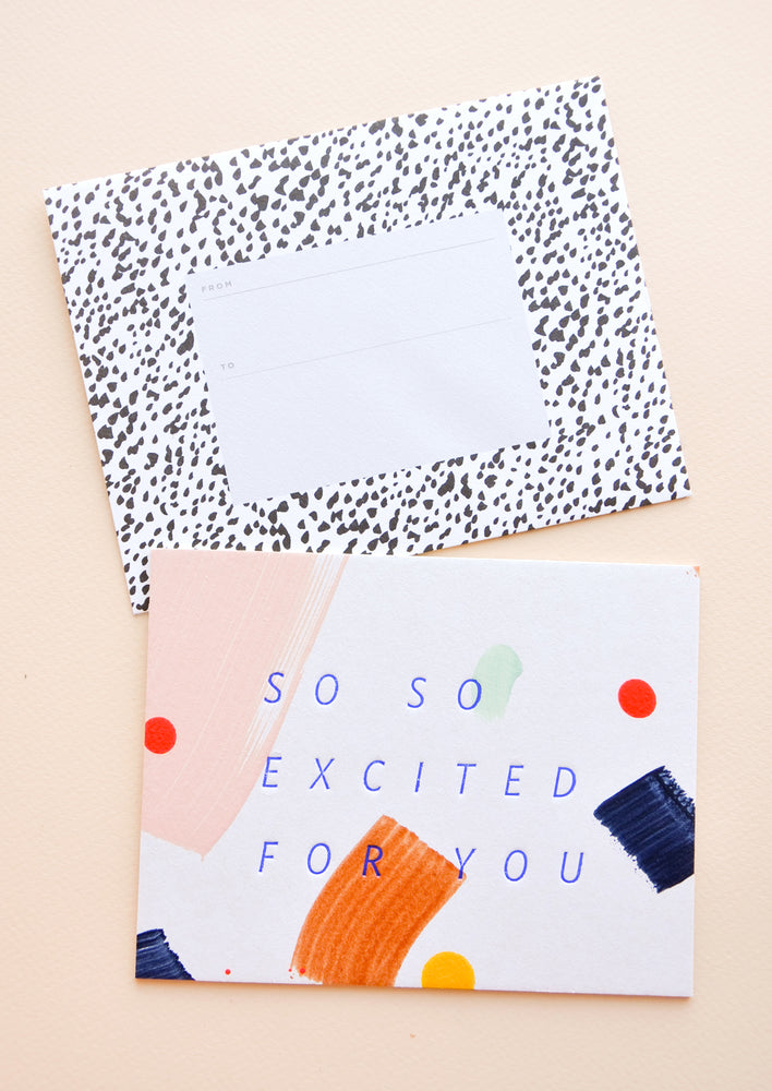 Notecard with colorful abstract shapes and the text "So So Excited For You", with spotted black and white envelope