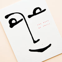 2: White minimalist greeting card with a simple black drawing of a smiling face and the words "you make me smile" in gold foil.