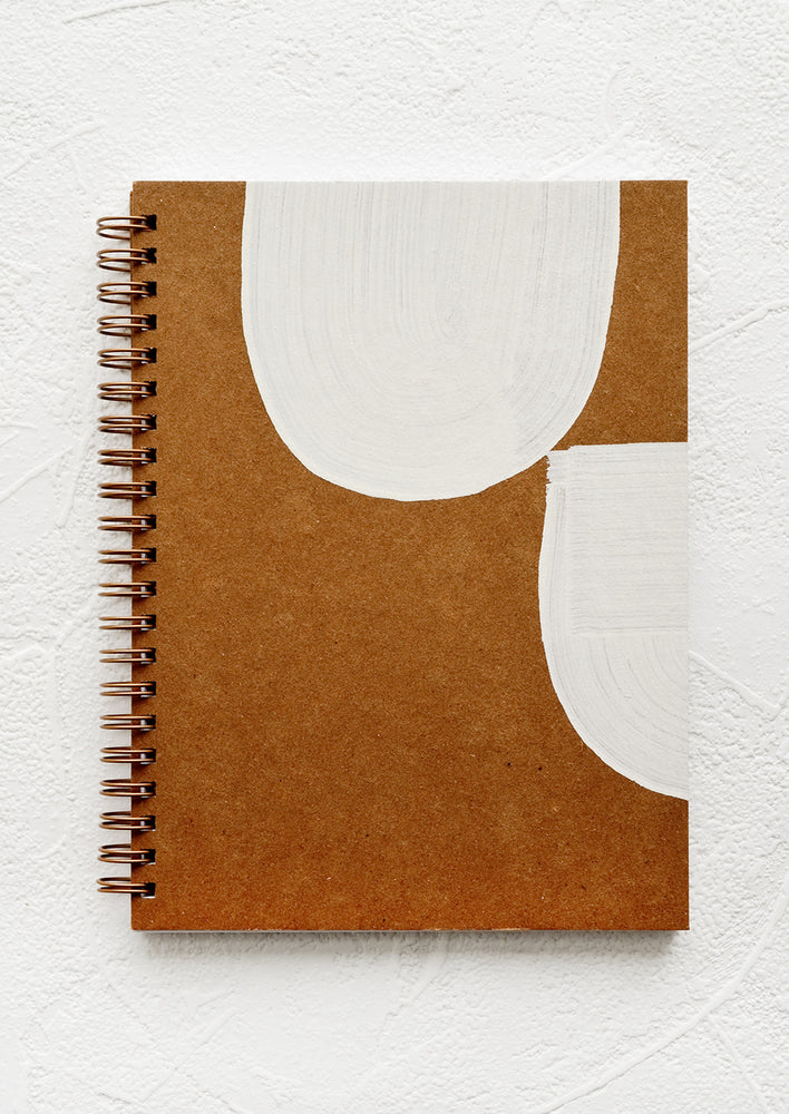 A kraft cover journal with hand painted white shapes on cover.