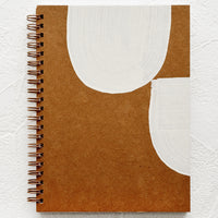 1: A kraft cover journal with hand painted white shapes on cover.