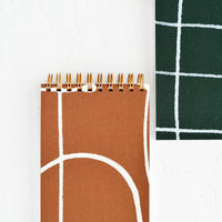 3: Small pocket sized, spiral bound notebooks in green and brown.