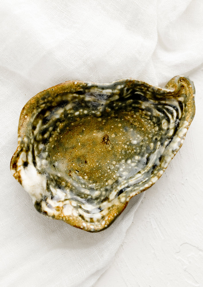 A shallow trinket catchall tray in shape of oyster shell.