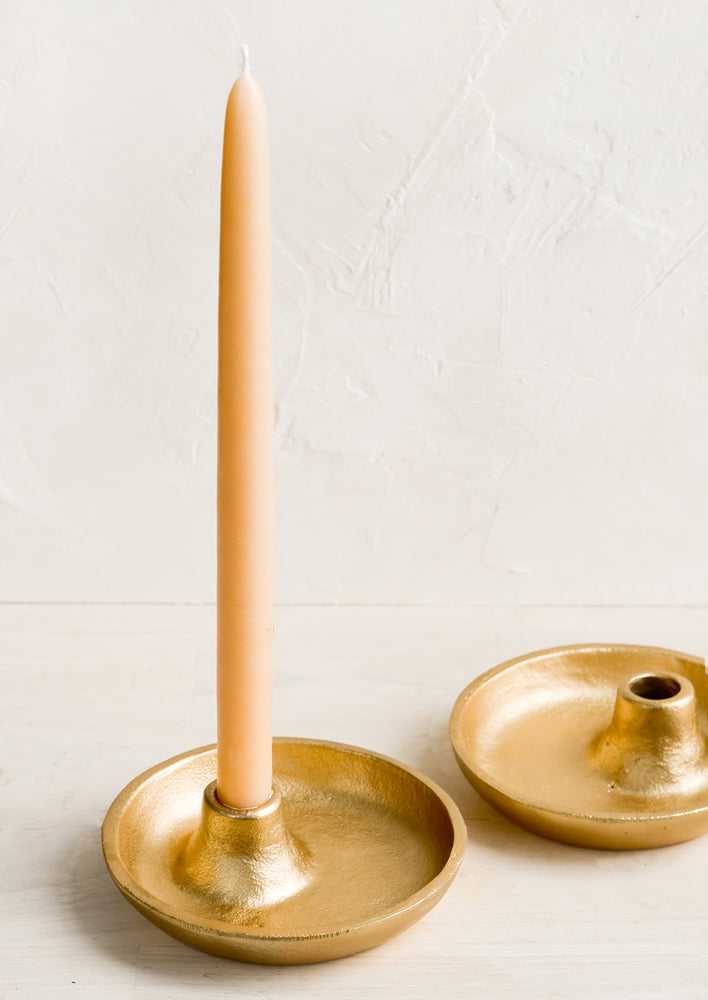 Matte gold taper candle holders, one with candle.