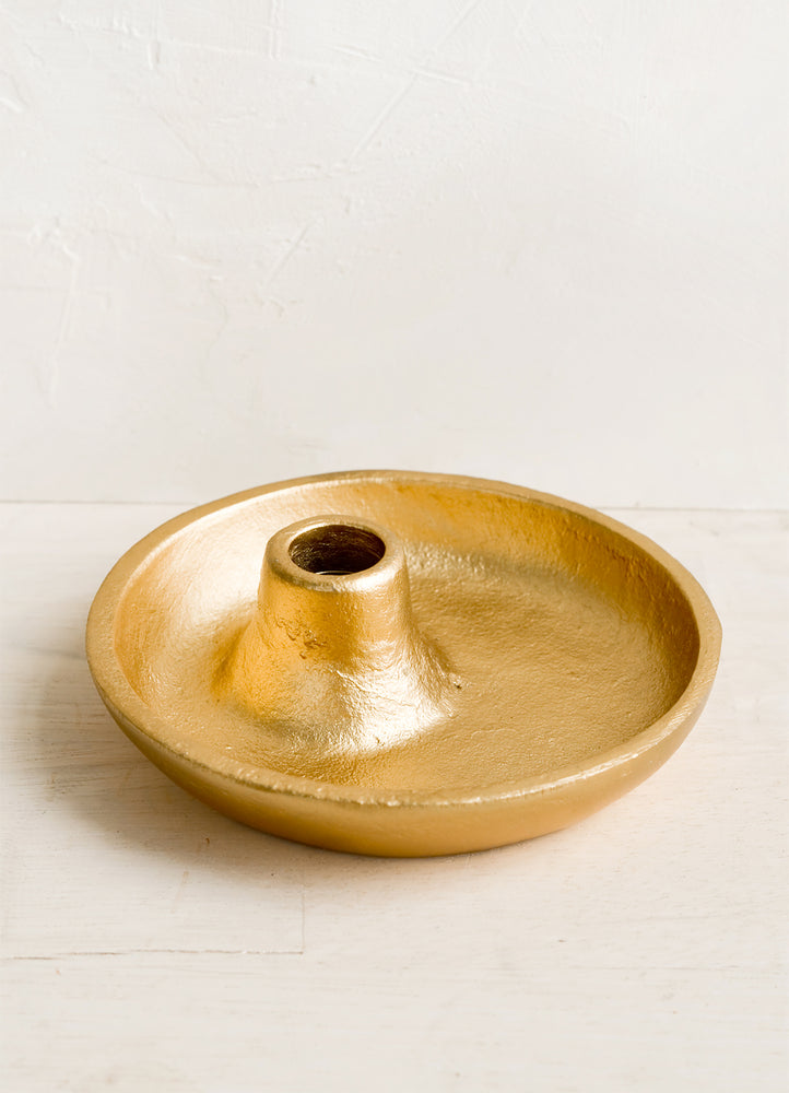 A matte gold taper holder with trivet style base.