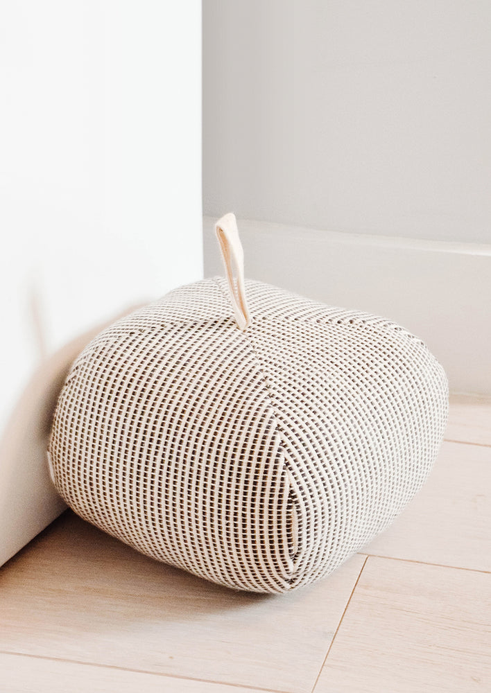 1: Cube-shaped upholstered doorstop, crafted in black and white dash print fabric with cotton loop at top.