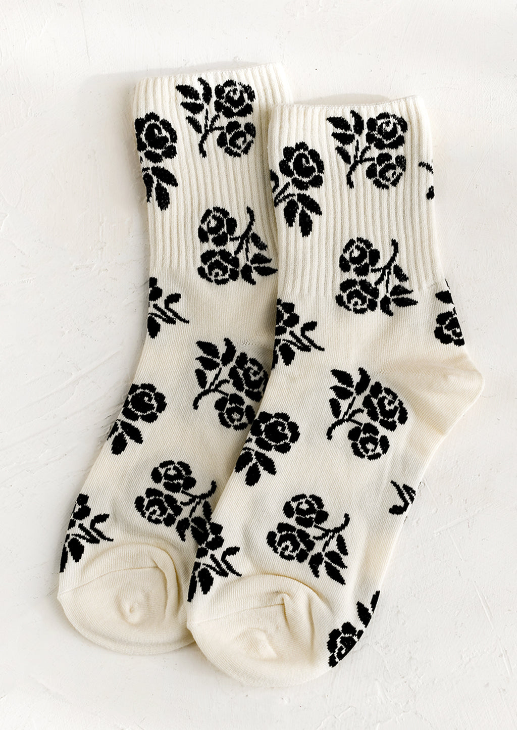 1: A pair of ivory socks with black floral print.