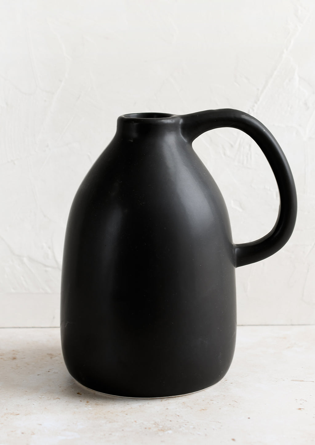 2: A black ceramic vase in jug shape with handle.